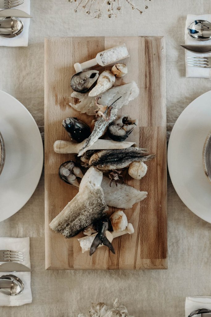 A fish board of sprats, cod skin, salted cod, scallops, squid + pickled mackerel for modern barn wedding