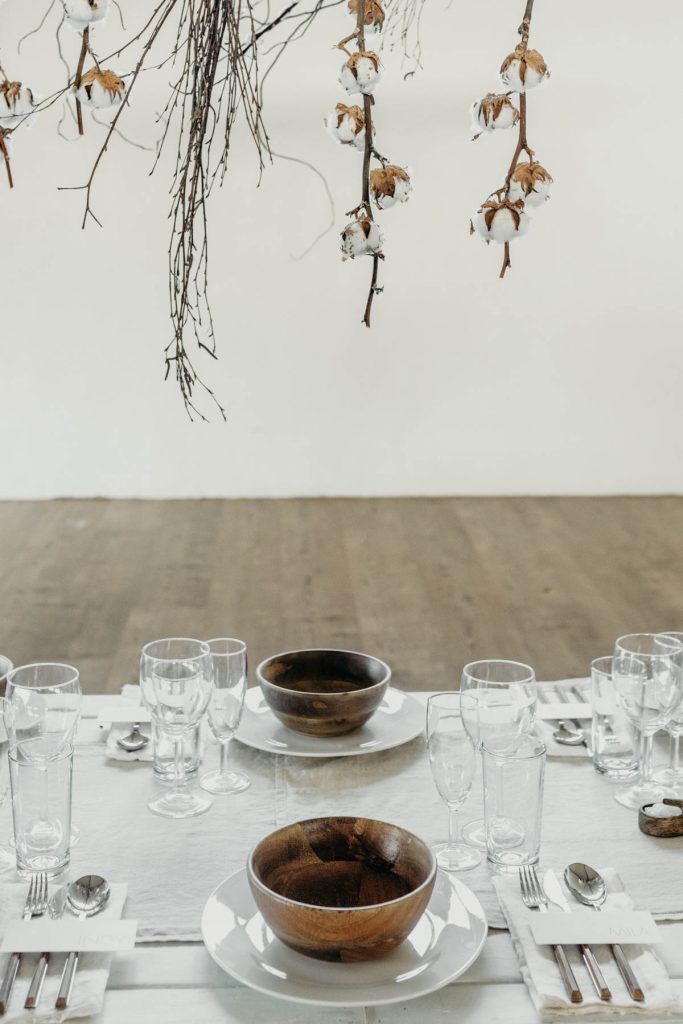 A clean, modern wedding breakfast tablescape of neutral tones and wooden accents