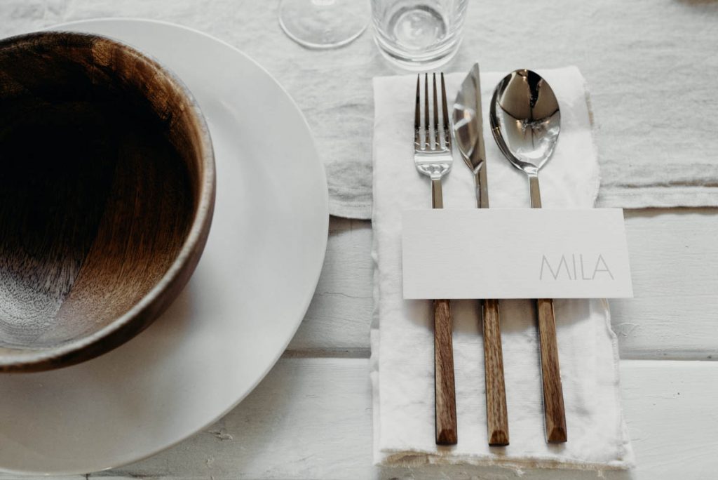 A clean, modern wedding breakfast tablescape of neutral tones and wooden accents