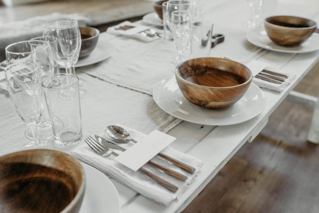 A clean, modern wedding breakfast tablescape of neutral tones and wooden accents
