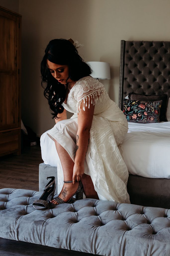 Bride wearing a bespoke Maggie Sottero boho style wedding dress with tasselled sleeves and a detachable veil cape