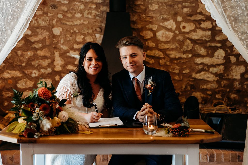 A newlywed bride and groom sign the registrar book during their wedding ceremony