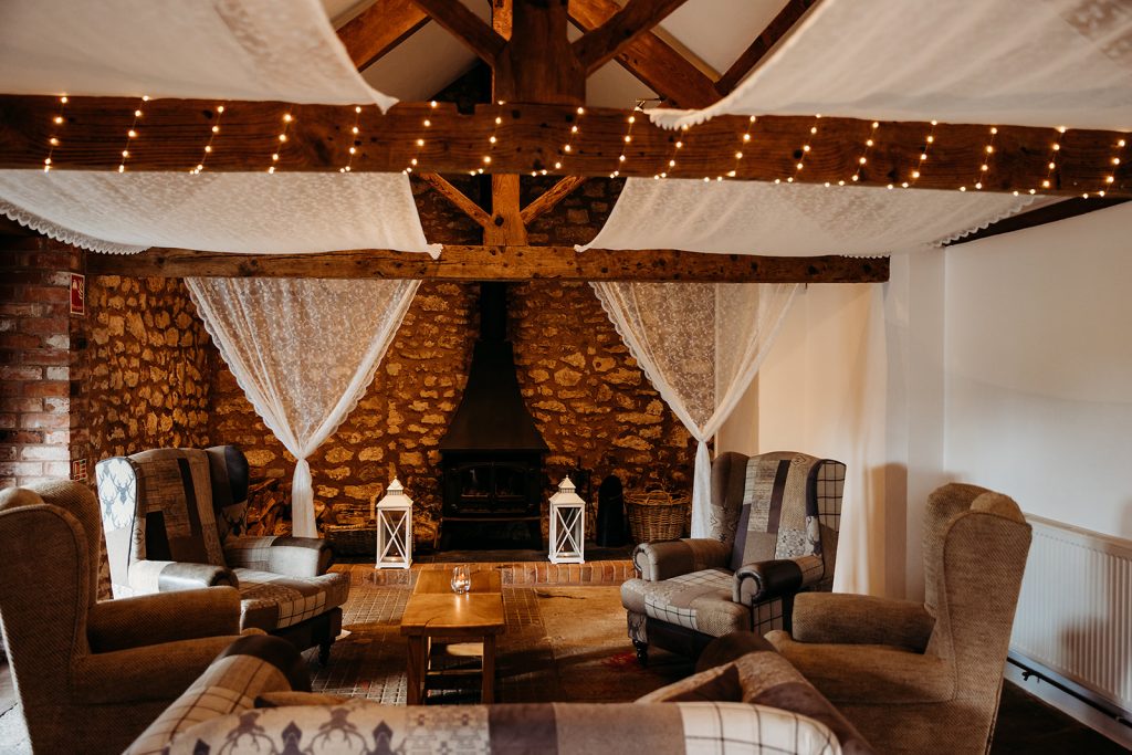 A lounge area with exposed brickwork walls and draped curtains hanging inside a Somerset wedding venue