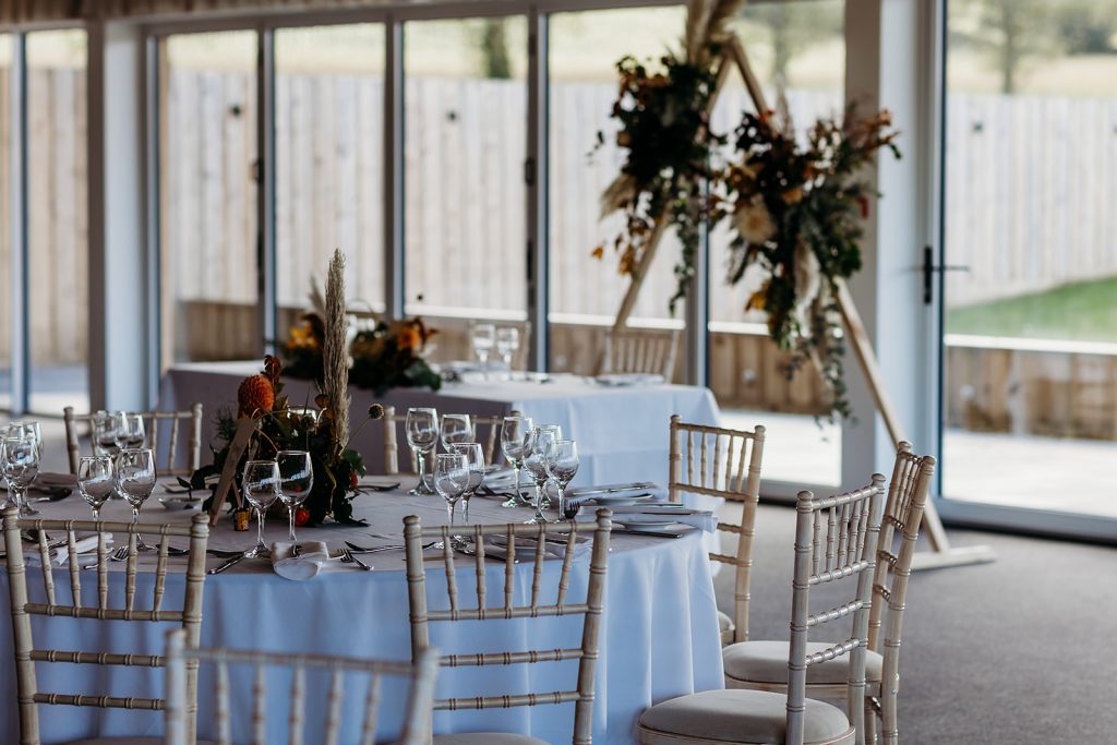 Autumn boho wedding breakfast styling with floral arch for boho couple