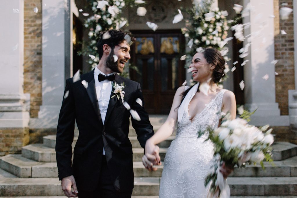 White confetti gently cascades down on top of a newly married winter wedding couple