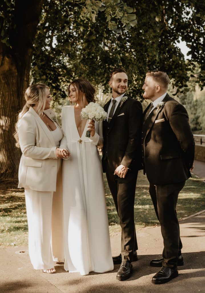 A bride and Groom stand laughing with their teo best friends who have just witnessed their intimate wedding ceremony