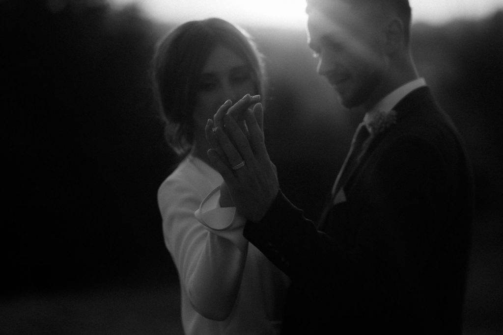 A city elopement for a chic modern couple who tenderly caress one another's hands during their sunset vows