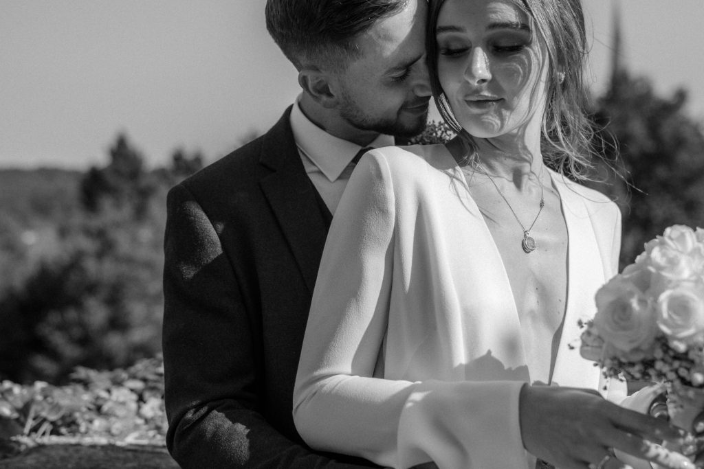A tender moment during portrait shots for newlyweds. The bride wears a long sleeved Galvan London dress