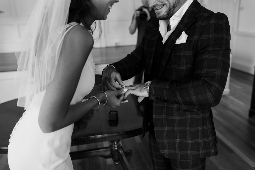 A groom puts a ring on his soon to be bride's finger during their wedding ceremony in Poole Registry office