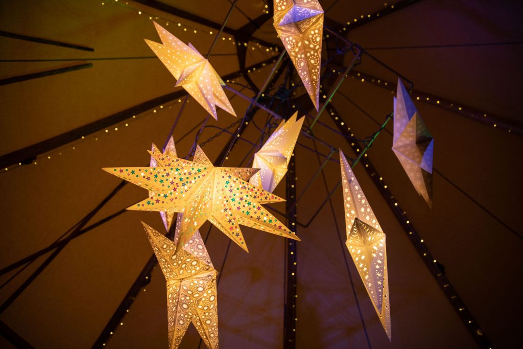 Paper star lanterns hang from the ceiling of a tipi to create a beautifully romantic atmosphere for boho wedding