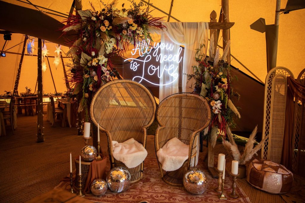 Peacock chairs, mirror balls, wedding backdrop and neon signage for cool chill out area in tipi wedding