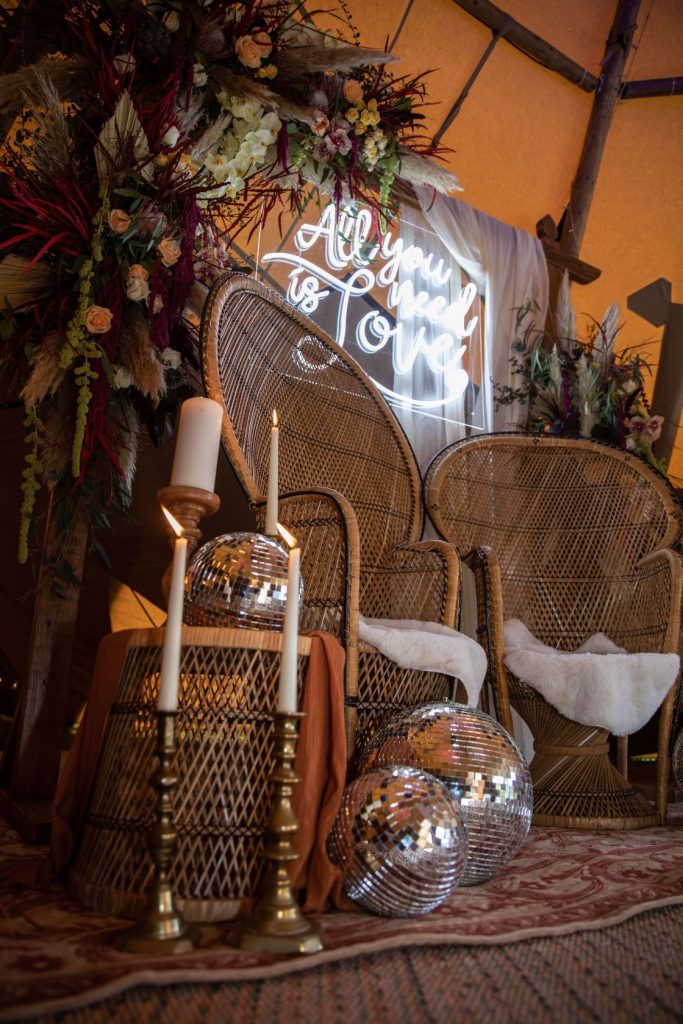 Peacock chairs, mirror balls, wedding backdrop and neon signage for cool chill out area in tipi wedding
