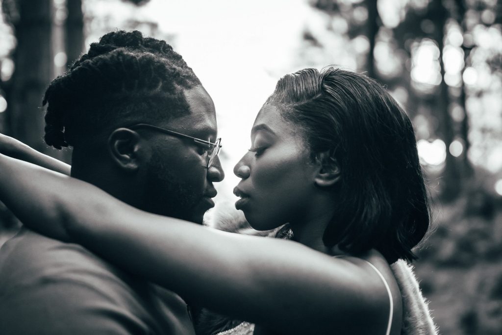 A beautiful black and white artistic wedding portrait of a newlywed couple in a tender embrace as they take part in an intimate wedding photo shoot. The bride has her arms wrapped gently around her husband's neck.