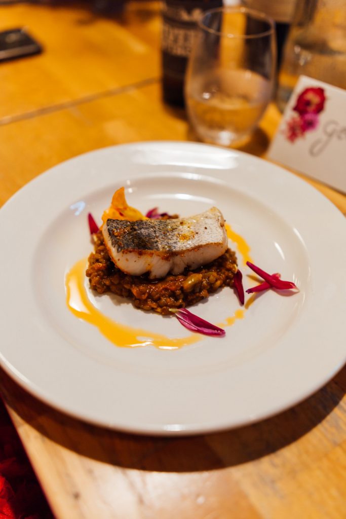 A beautifully presented fish dish on a white china plate prepared for wedding guests at a non-traditional wedding celebration at River Cottage.