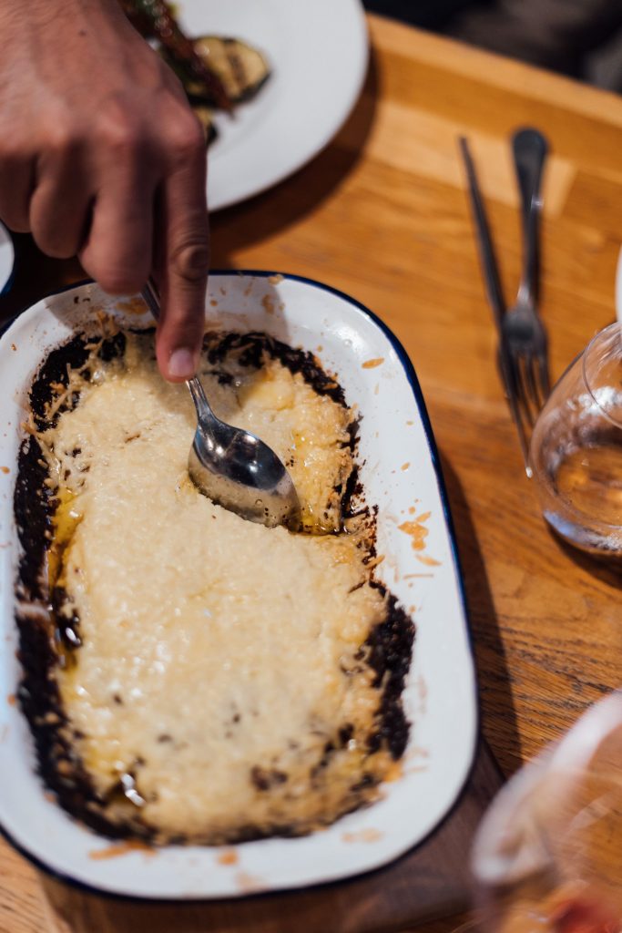 A homemade crumble served in a old fashioned tin is being served with a spoon during a non-traditional wedding celebration at River Cottage where ingredients are locally sourced, organic and fresh.