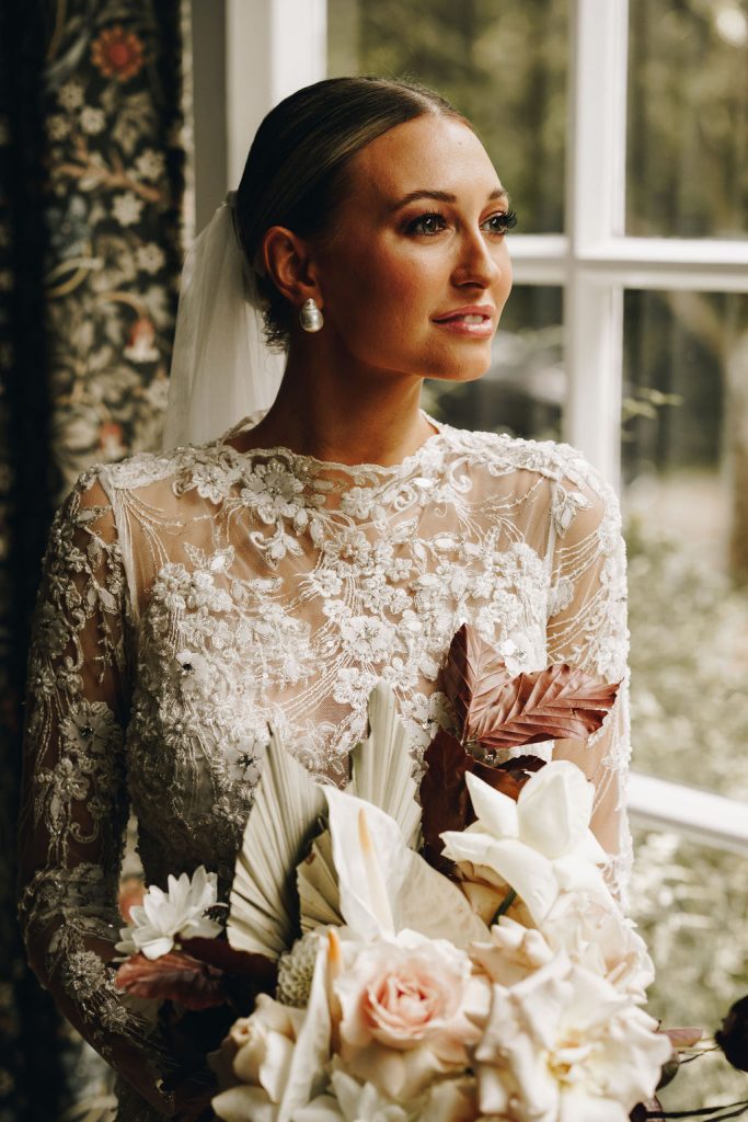 Beautiful bride in a long sleeved, high neck, embellished Yolancris wedding gown