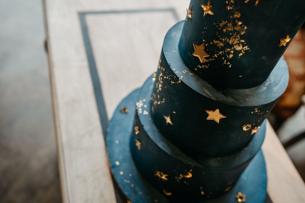 A three tiered blue and gold celestial themed wedding cake for queer wedding couple Jenn + Georgie