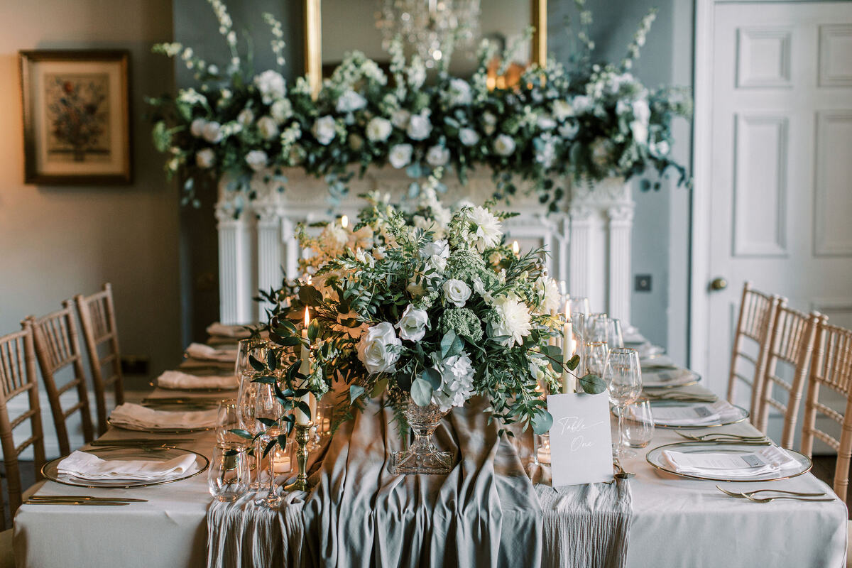 An elegant wedding tablescape with green + white florals and hints of gold