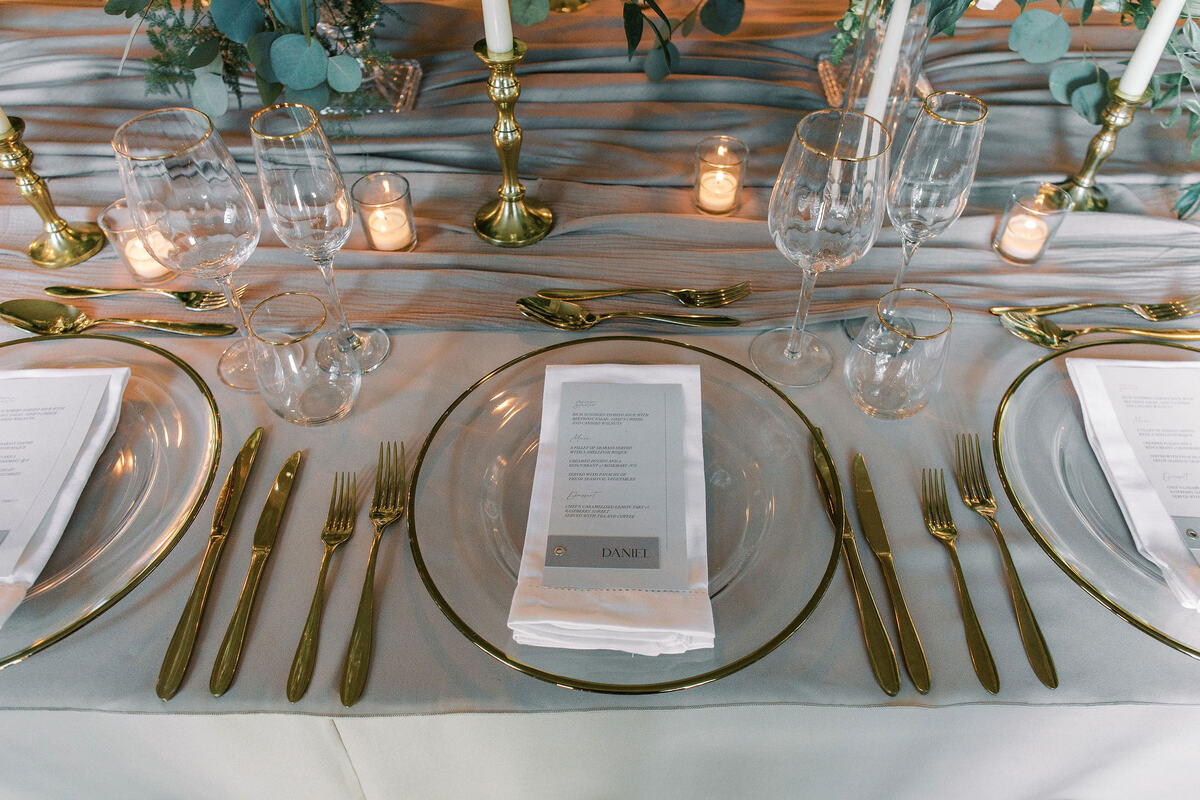 An elegant wedding tablescape with green + white florals and hints of gold