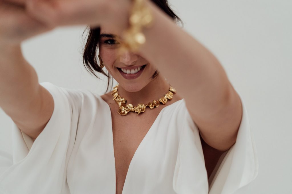 A bride wears a minimalist white wedding jumpsuit made with ethical and sustainable, vegan fabrics.
