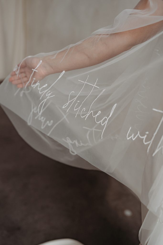 A custom made elegant veil with hand stitched embroidered script writing along the hem of the veil.