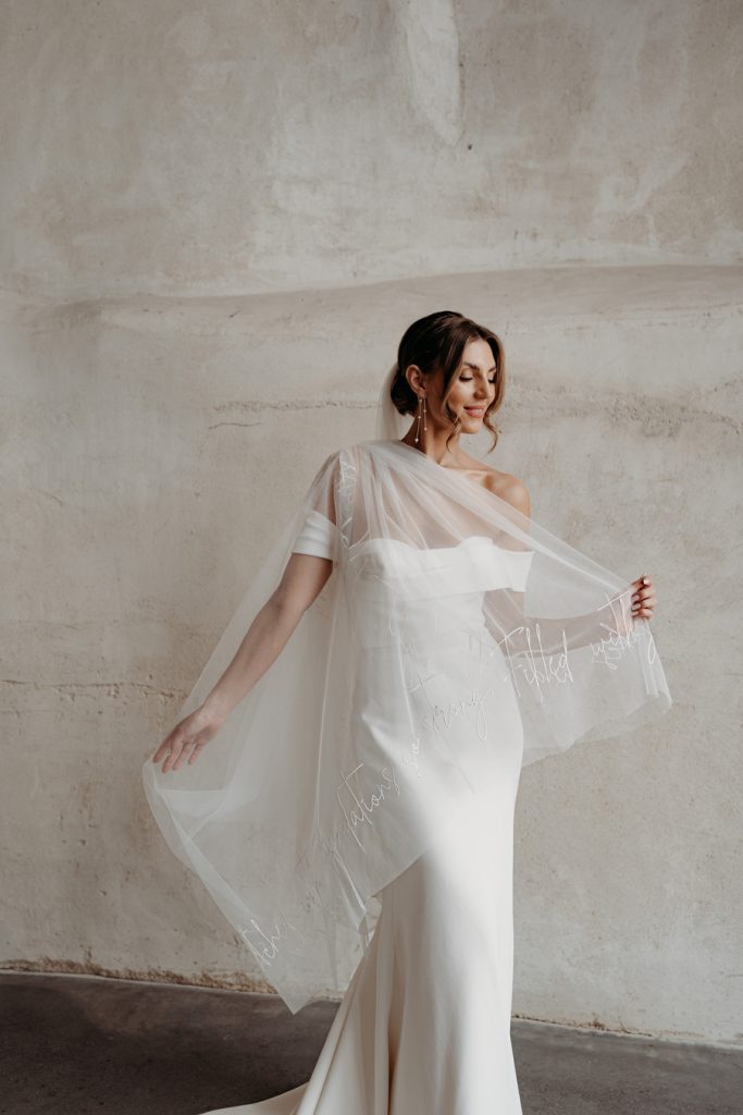 A custom made elegant veil with hand stitched embroidered script writing along the hem of the veil.
