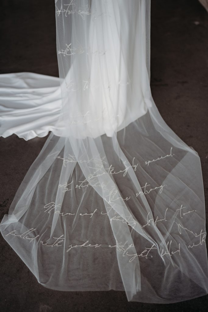 A long length custom embroidered wedding veil with script writing of a verse of a poem carefully embroidered along the entire length of the veil.