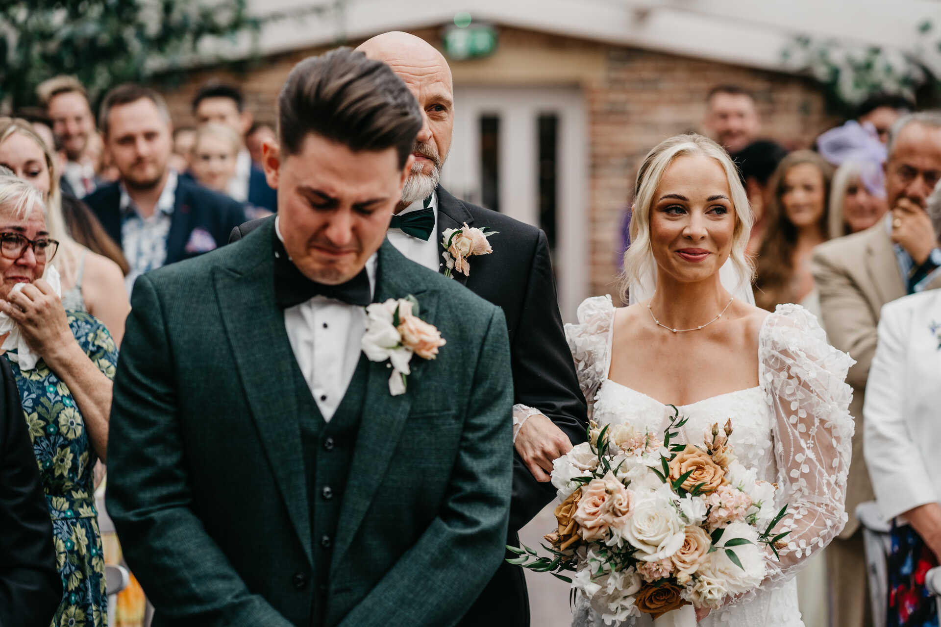 An emotional moment for groom David as his soon to be wife approaches behind during their ceremony
