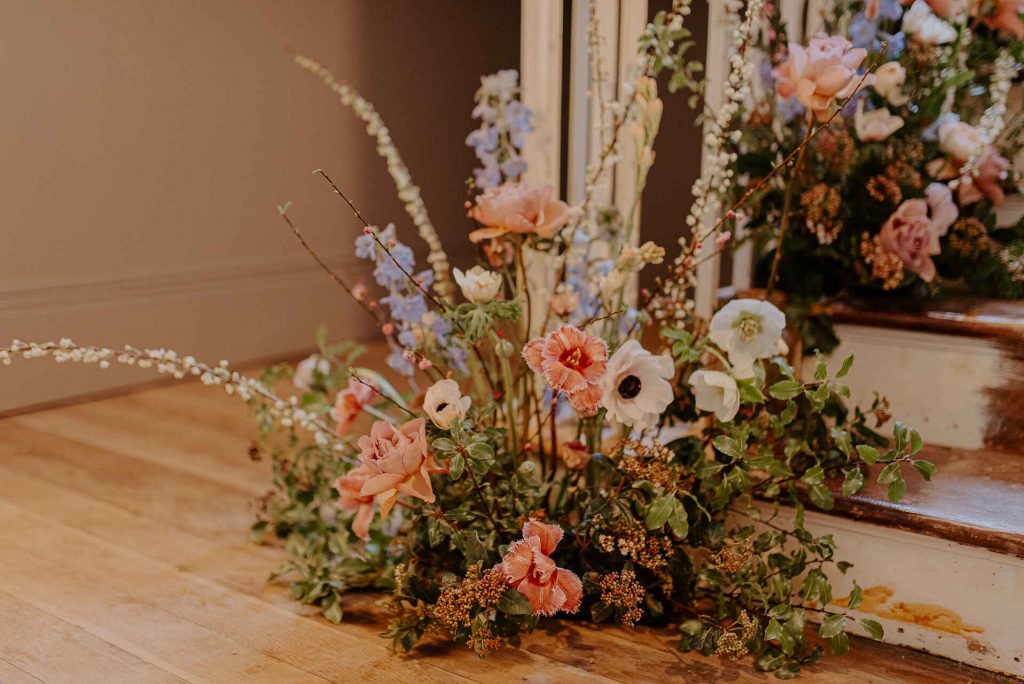 A beautiful fresh floral cluster creating a feature statement at the bottom of the wooden stairway at Cornwall's Polstrong Manor