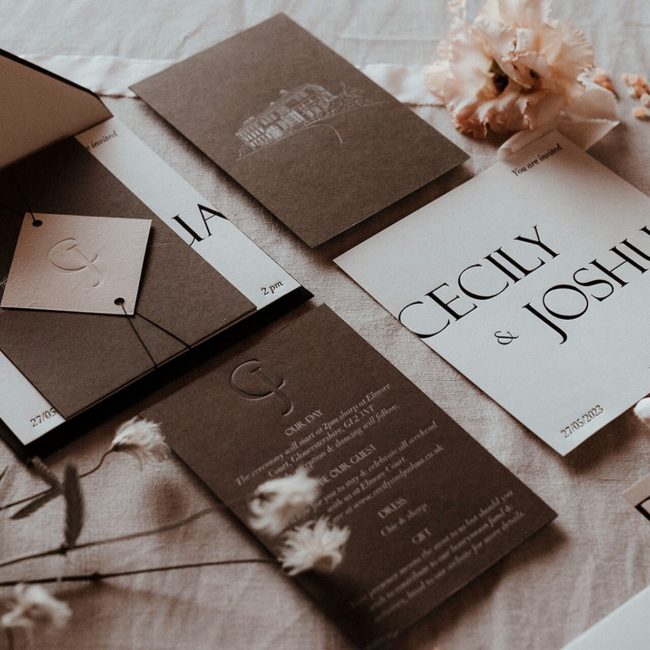 An elegant flat lay brown and white wedding invitation suite, embellished with fresh flowers for a modern, contemporary look.