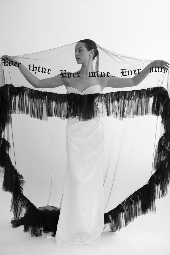 An elegant sheer veil with the most dramatic of hems with a bold, textural frill ruffle lining the length of the hem for a serious statement bridal piece. The words Ever thine, Ever mine, Ever ours are embroidered in black gothic style thread.